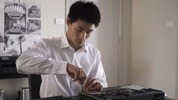 Information technology student Adrian Chen working on pc